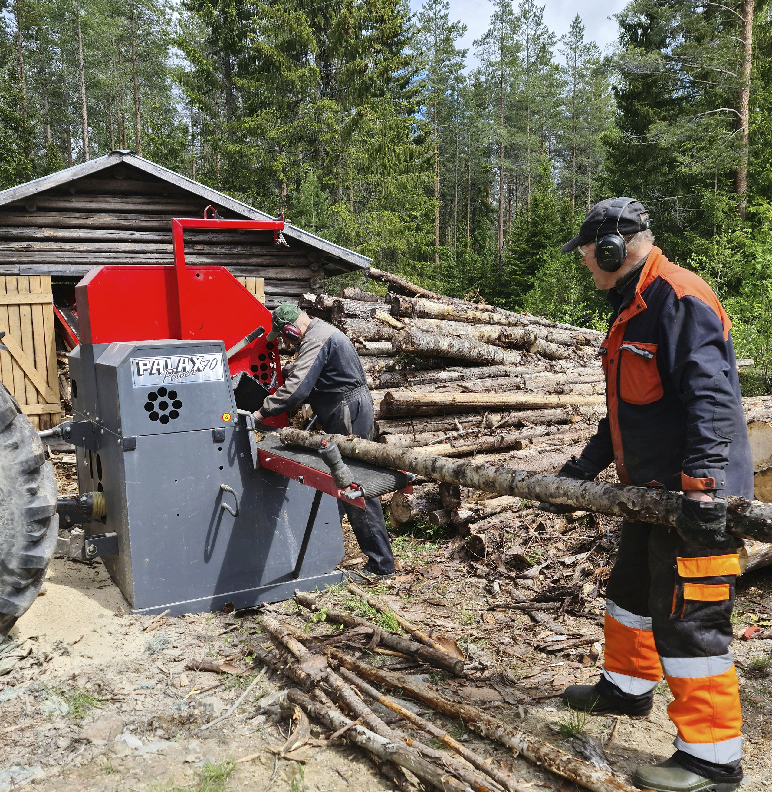 Kaksi miestä pilkkoo puita klapikoneella.