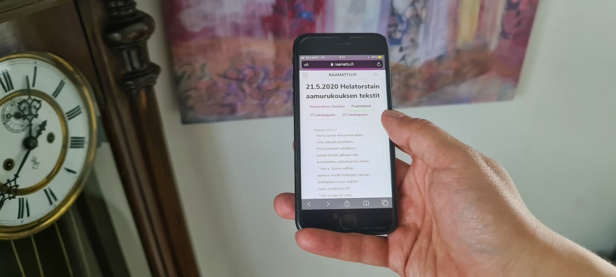 Kädessä olevassa kännykässä näkyy rukouspalvelun nettisivu. Kuva: Suomen Pipliaseura